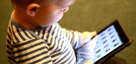 dziecko przedszkolne siedzi na podłodze z tabletem w rękach, skupione na ekranie