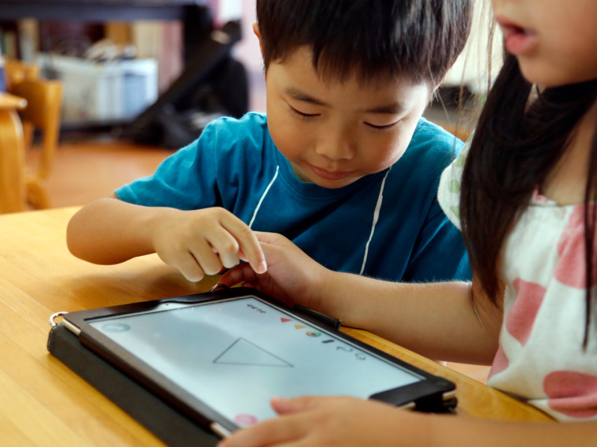 matka i syn dzielą tablet, oboje patrzą na ekran z zabawkami w tle